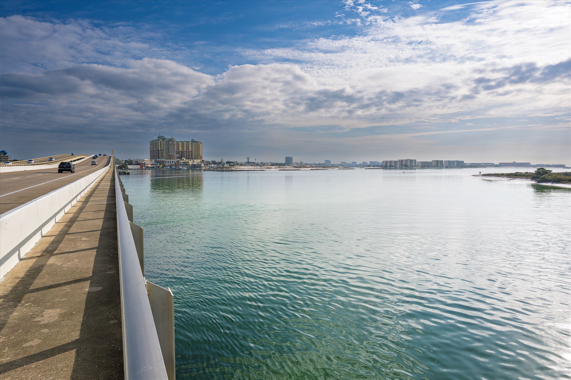 vehicle bridge with walking path at destin harbor vehicle bridge with walking path blue sky blue water no people cars and trucks at destin harbor by Terry Kelly Photography