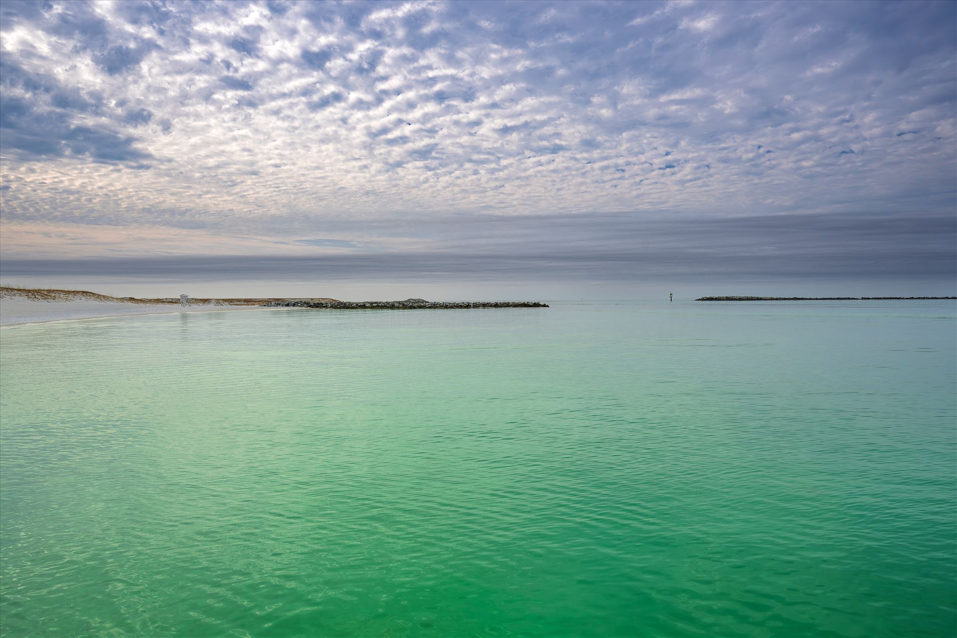 white sandy beach with emerald-green waters of Destin Harbor A quiet moment on the coast, a white sandy beach with emerald-green waters of Destin Harbor, with a lifeguard stand standing watch beneath the open sky, ready for sunny days and salty breezes. by Terry Kelly Photography