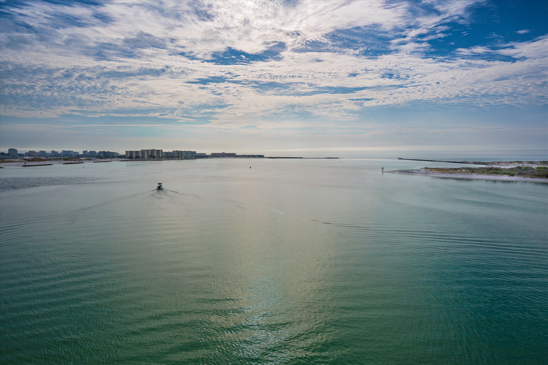 Boat departing Destin Harbor Boat departing Destin Harbor, cruising through emerald waters under a cloudy blue sky. by Terry Kelly Photography