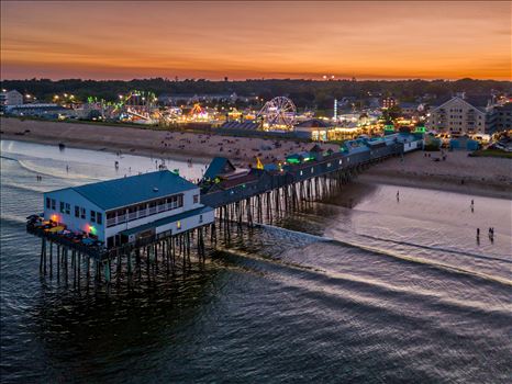 Amusement park lights twinkle to life behind the historic Old Orchard Beach Pier in Old Orchard Beach, Maine by New England Photography