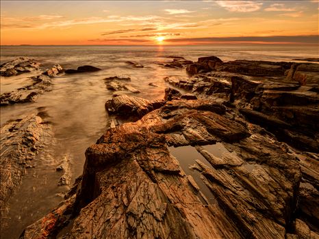Golden sunrise illuminates a rocky outcrop near Two Lights State Park in Cape Elizabeth, Maine. by New England Photography