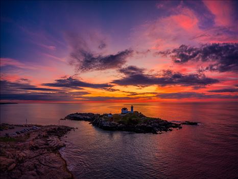 The sky is ablaze just before dawn at Cape Neddick "Nubble Light" Lighthouse" in York, Maine by New England Photography