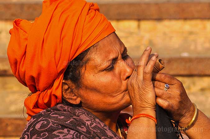 Culture- Naga Sadhu’s (India) A women Naga Sadhu enjoying clay pipe smoking at Varanasi ghat. by Anil