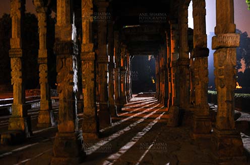 Monuments- Qutab Minar in Night, New Delhi, India. The Beauty of Hindu Columns with stone carving at Quwwat-Ul-Islam mosque courtyard in night at Qutub Minar Complex, New Delhi, India. by Anil