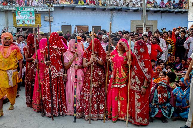 Festivals- Lathmaar Holi of Barsana (India) women's wearing colorfull saree's holding bamboo sticks during Lathmaar Holi at Barsana, Mathura, Uttar Pradesh, India. by Anil