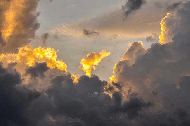 Clouds- Sky with Clouds (Uttarkashi) Uttarkashi, Uttarakhand, India-  June 12, 2013: light Blue sky in the evening with yellow-orange clouds over the hills of Uttarkashi, India. (Photo By Anil Sharma) by Anil
