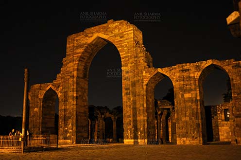 Monuments- Qutab Minar in Night, New Delhi, India. The Beauty of arches of Iltutmish screen and some tourists standing near the iron pillar in night at Qutub Minar Complex, Mehrauli , New Delhi, India. by Anil