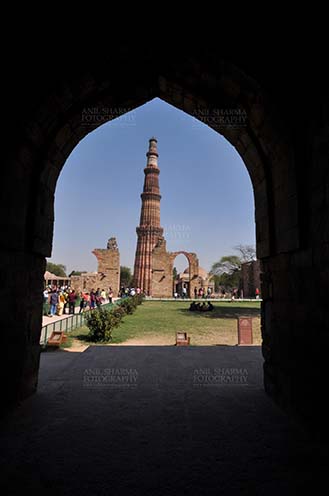 Monuments- Qutab Minar, New Delhi, India. Qutub Minar the tallest brick minaret in the world seen through arch at Qutub Minar Complex, New Delhi, India. by Anil