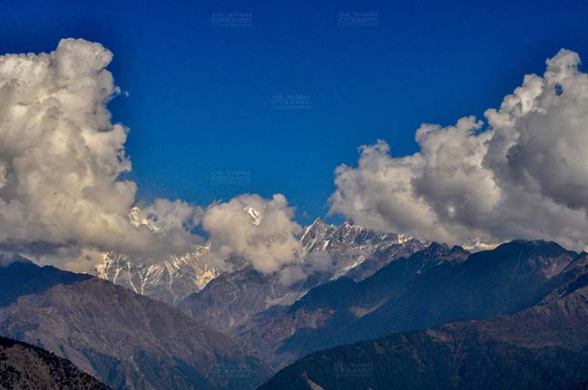 Clouds- Sky with Clouds (Panchchuli Peaks) Panchchuli Peaks, Munsiyari, Uttarakhand, India- November 2, 2016: Blue sky with Bright white  clouds floating over the snow covered Punchchuli Peaks view from Munsiyari, Uttarakhand, India. by Anil