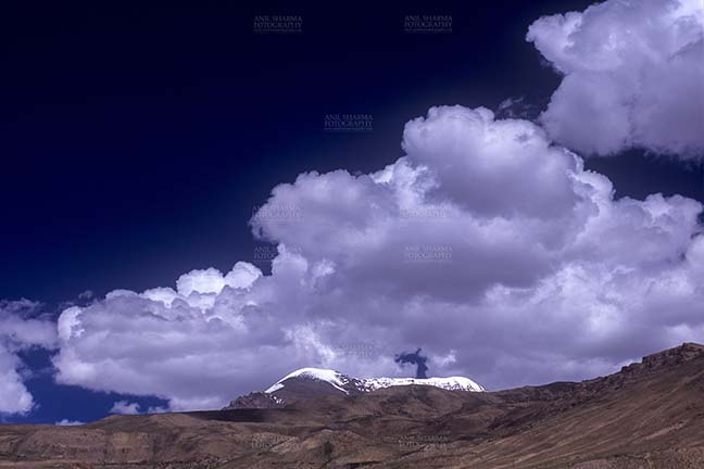 Clouds- Sky with Clouds (Kibber) Sky with Clouds, Kibber, Spiti Valley, Himachal Pradesh, India- December 13, 2006: Dark blue sky with white clouds over the snow covered peaks at Kibber, Lahaul-Spiti, Himachal Pradesh, India. by Anil