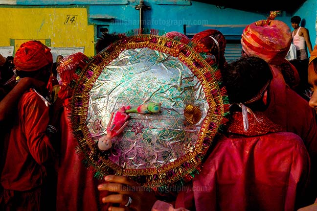 Festivals- Lathmaar Holi of Barsana (India) A man daubed in color powder holding shield during Lathmaar Holi celebration at Barsana, Mathura Uttar Pradesh, India. by Anil