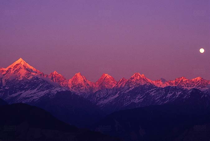Mountains- Panchchuli Peaks (India) Pink color Panchchuli Peaks and full moon in the sky view from Munsyari at Uttarakhand, India. by Anil