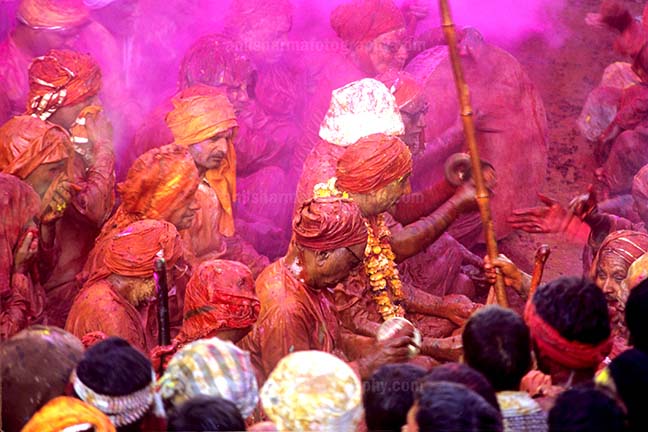 Festivals- Lathmaar Holi of Barsana (India) People daubed in colored water, head covered singing a hymn during Lathmaar Holi celebrations at Barsana, Mathura, India. by Anil