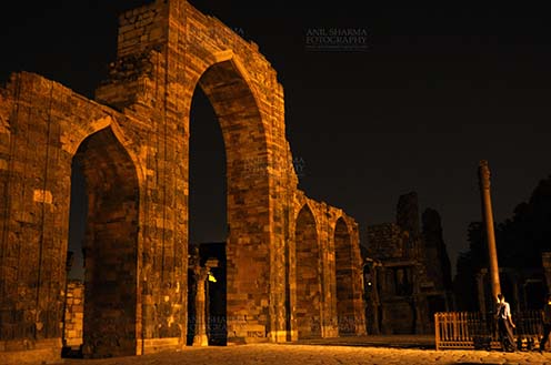 Monuments- Qutab Minar in Night, New Delhi, India. The Beauty of arches of  Iltutmish screen and some tourists standing near the  iron pillar in night at Qutub Minar Complex, Mehrauli , New Delhi, India. by Anil