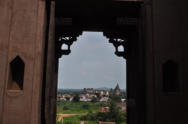 Monuments- Palaces and Temples of Orchha Orchha, Madhya Pradesh, India- August 20, 2012: View from a carved window of Laxmi Temple, Chaturbhuj temple is seen in the distance, Orchha, Madhya Pradesh, India. by Anil