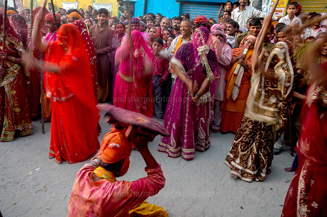 Festivals- Lathmaar Holi of Barsana, Mathura, Uttar Pradesh, India. (photo: Atul Sharma) A man from Nandgaon is protecting himself from the women of Barsana hitting on his shield with their sticks during Lathmaar Holi at Barsana. by Anil