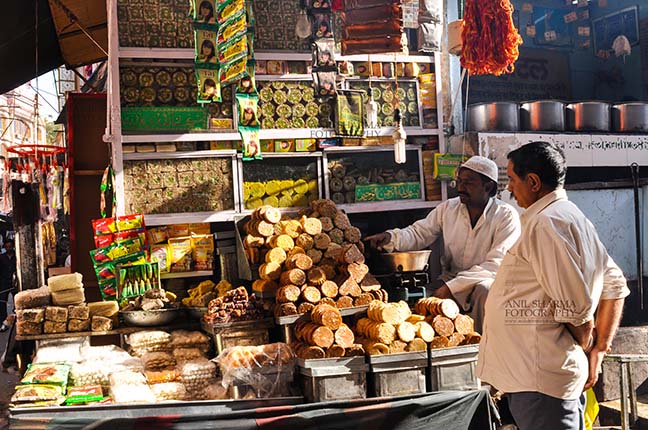 Religion- Dargah Sharif, Ajmer, Rajasthan (India) Savouries and sweet Shops at shrine market place of Ajmer Sharif Dargah the Mausoleum of Moinuddin Chishti, a sufi saint from India at Ajmer, Rajasthan, India. by Anil
