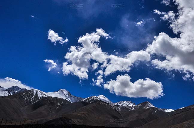 Clouds- Sky with Clouds (Pangong Tso) Clouds over Pangong Tso, Leh, Jammu and Kashmir, India- October 1, 2014: Dark blue sky with Bright white clouds over the Pangong Tso and surrounding hills at Leh, Jammu and Kashmir, India. by Anil