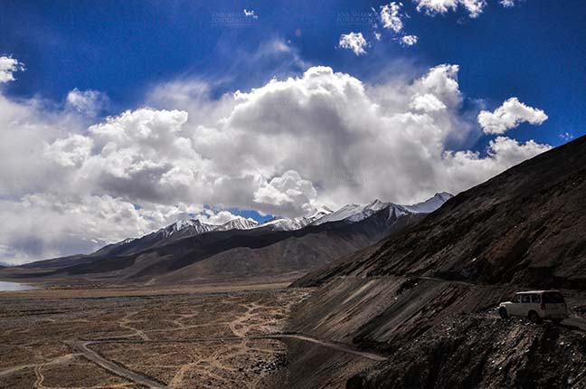 Clouds- Sky with Clouds (Pangong Tso, Leh) Clouds over Pangong Tso, Leh, Jammu and Kashmir, India- October 1, 2014: Dark blue sky with Bright white clouds over the Pangong Tso and surrounding hills at Leh, Jammu and Kashmir, India. by Anil