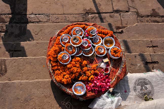 Travel- Varanasi the city of light (India) Hindu devotees use marigold and rose flowers, cotton, ghee, sweets and red powder in puja. by Anil