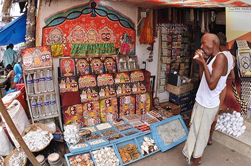 Festivals- Jagannath Rath Yatra, Puri, Odisha, India. (Photo:  Atul Sharma) Memento of Lord Jagannath, Balbhadra and Subhadra on display and an old customer at the shop near Lord Jagannath Temple at Puri, Odisha, India. by Anil