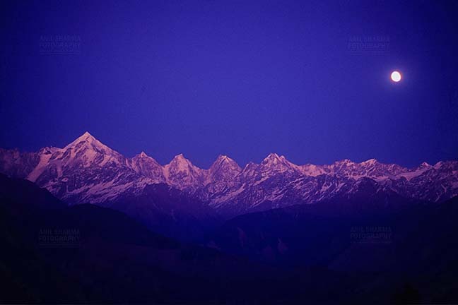 Mountains- Panchchuli Peaks, Munsyari, Uttarakhand, India. (Photo: Atul Sharma) Pink color Panchchuli Peaks and full moon in the blue sky, view from Munsyari at Uttarakhand, India. by Anil