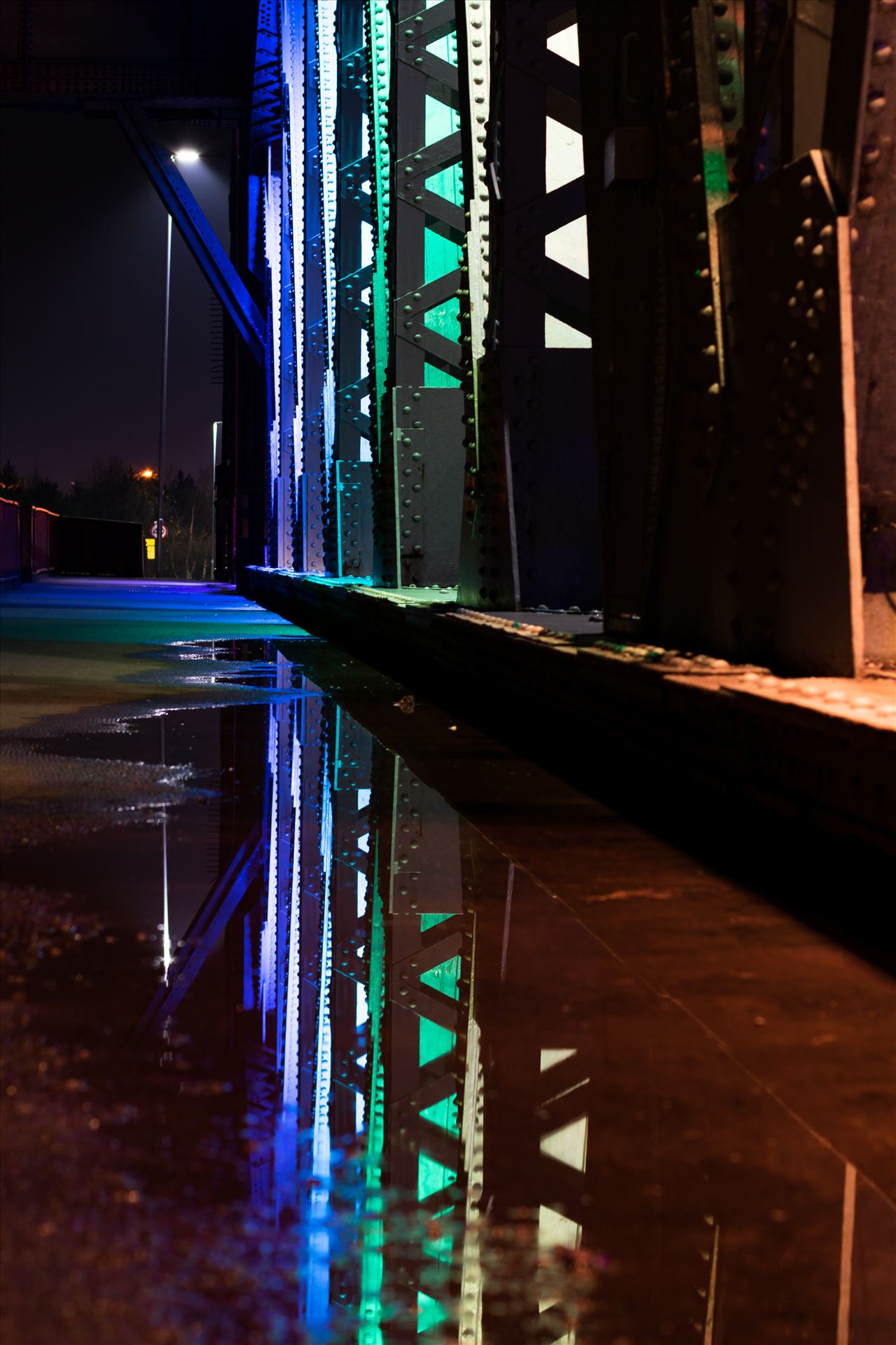 Newport Bridge Rainbow Lights Puddle Refrlection A photo of the lights on Newport Bridge and a puddle reflection. by AJ Stoves Photography