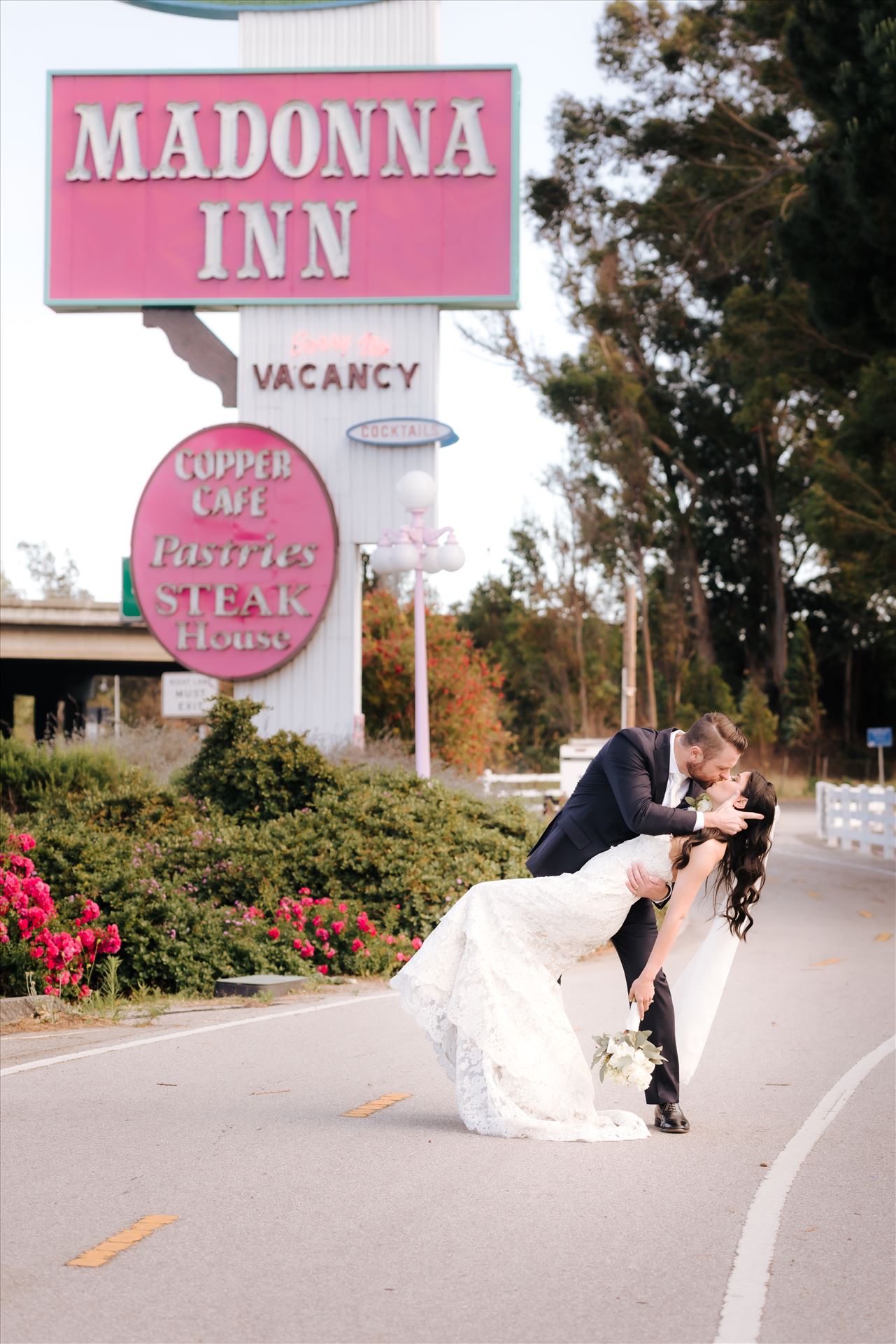 SP Gallery-5770.JPG Mirror's Edge Photography captures Xochitl and David's magical Madonna Inn Wedding in San Luis Obispo, California. Bride and Groom dip kiss in front of Madonna Inn Sign. by Sarah Williams