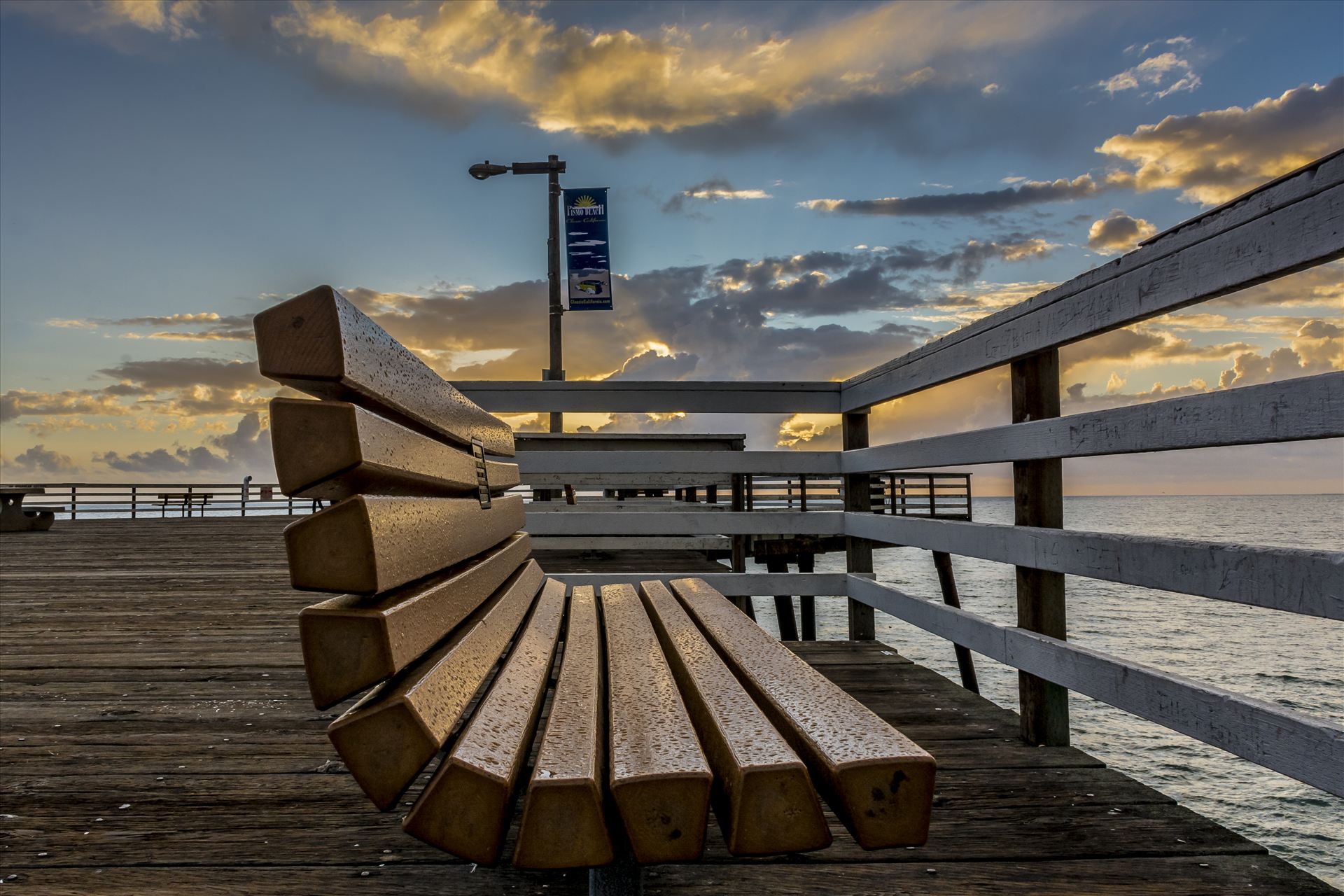 Rainy Bench.jpg Rain slicked bench on Pismo Beach pier at sunset by Sarah Williams