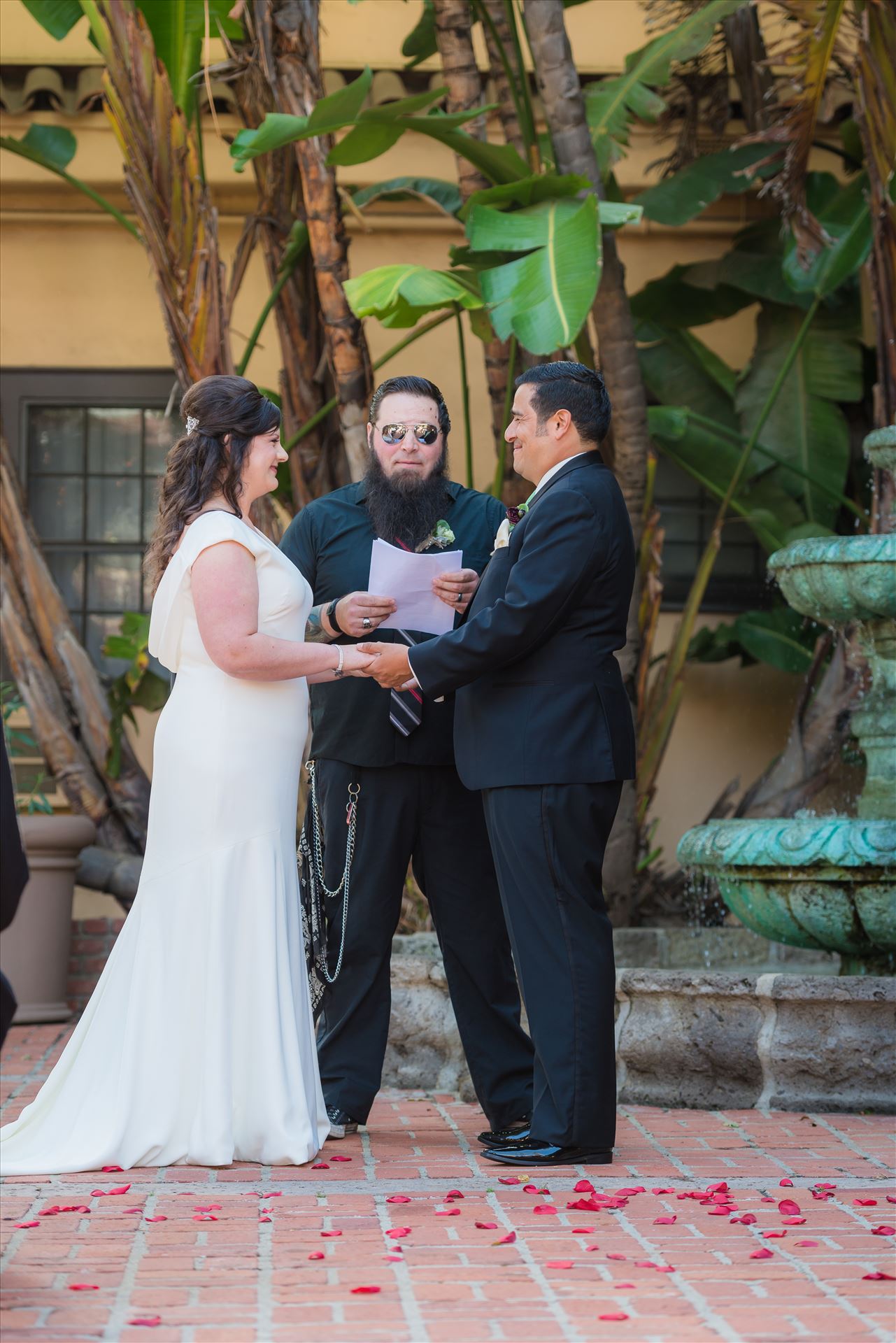 Mary and Alejandro 29 Wedding photography at the Historic Santa Maria Inn in Santa Maria, California by Mirror's Edge Photography. Bride and Groom exchange rings in courtyard by Sarah Williams