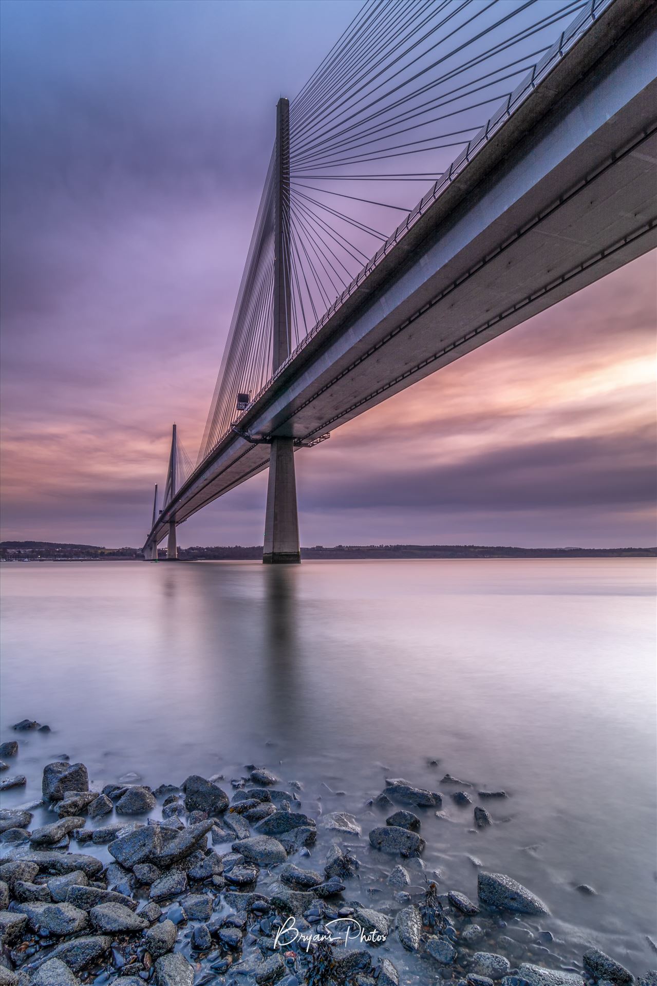 The Crossing A portrait photograph of the Queensferry Crossing taken from North Queensferry at sunset. by Bryans Photos