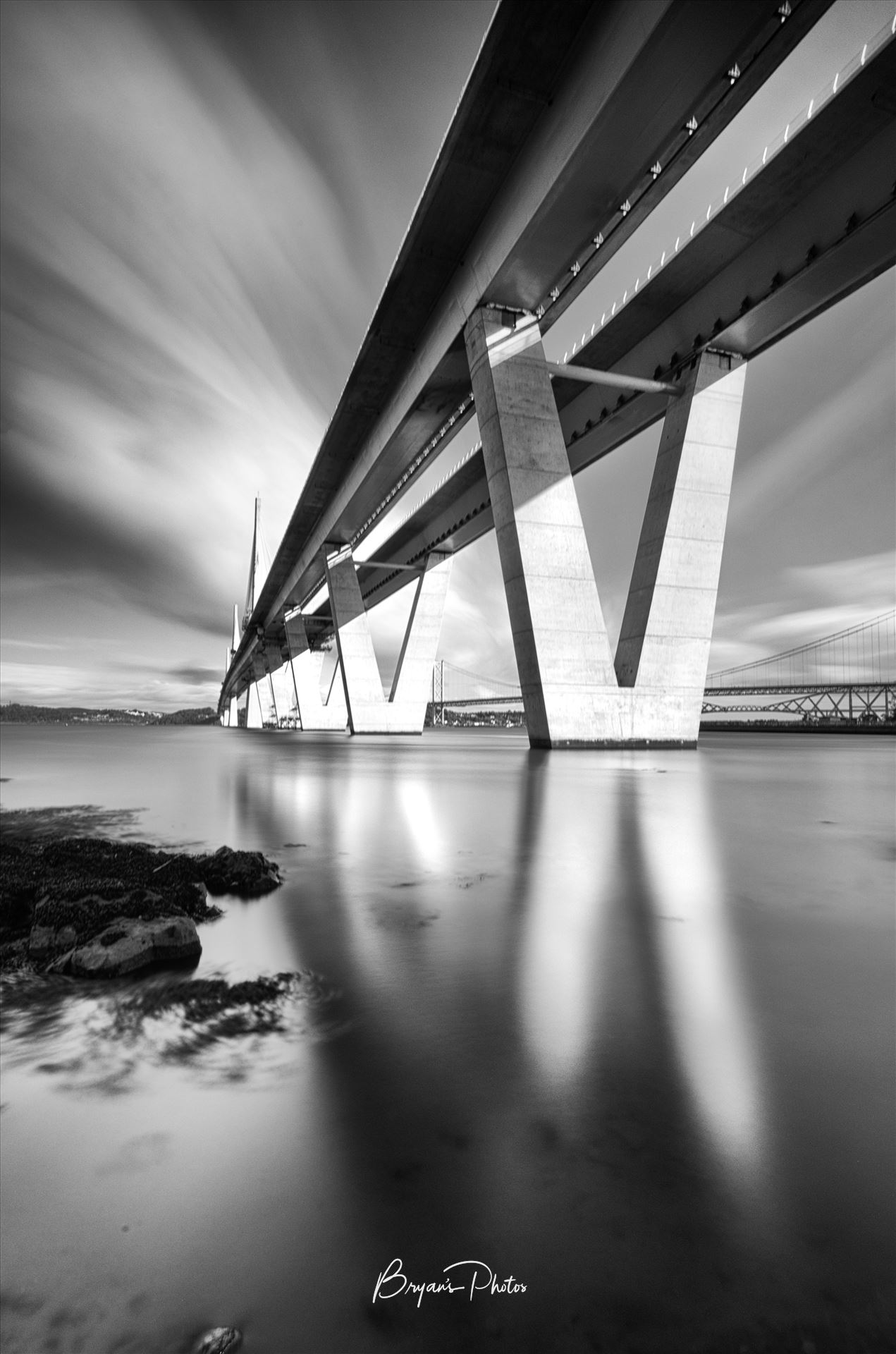The Crossing Portrait A black and white long exposure photograph of the Queensferry Crossing taken from the south bank of the river Forth at high tide. by Bryans Photos